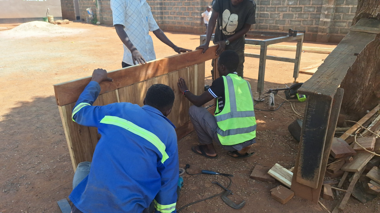 Young men at the All Is Grace campus work together to build a wooden door as part of their carpentry skills training.