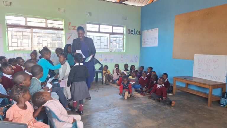 Overcrowded classroom at All Is Grace School in Zambia showing challenging teaching conditions as one teacher instructs two groups of children in the same room.