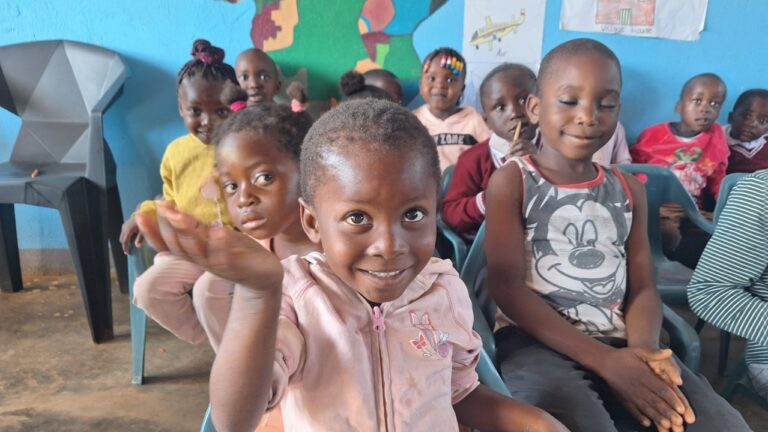 Children smiling and interacting inside a school for orphans run by All Is Grace School in Zambia