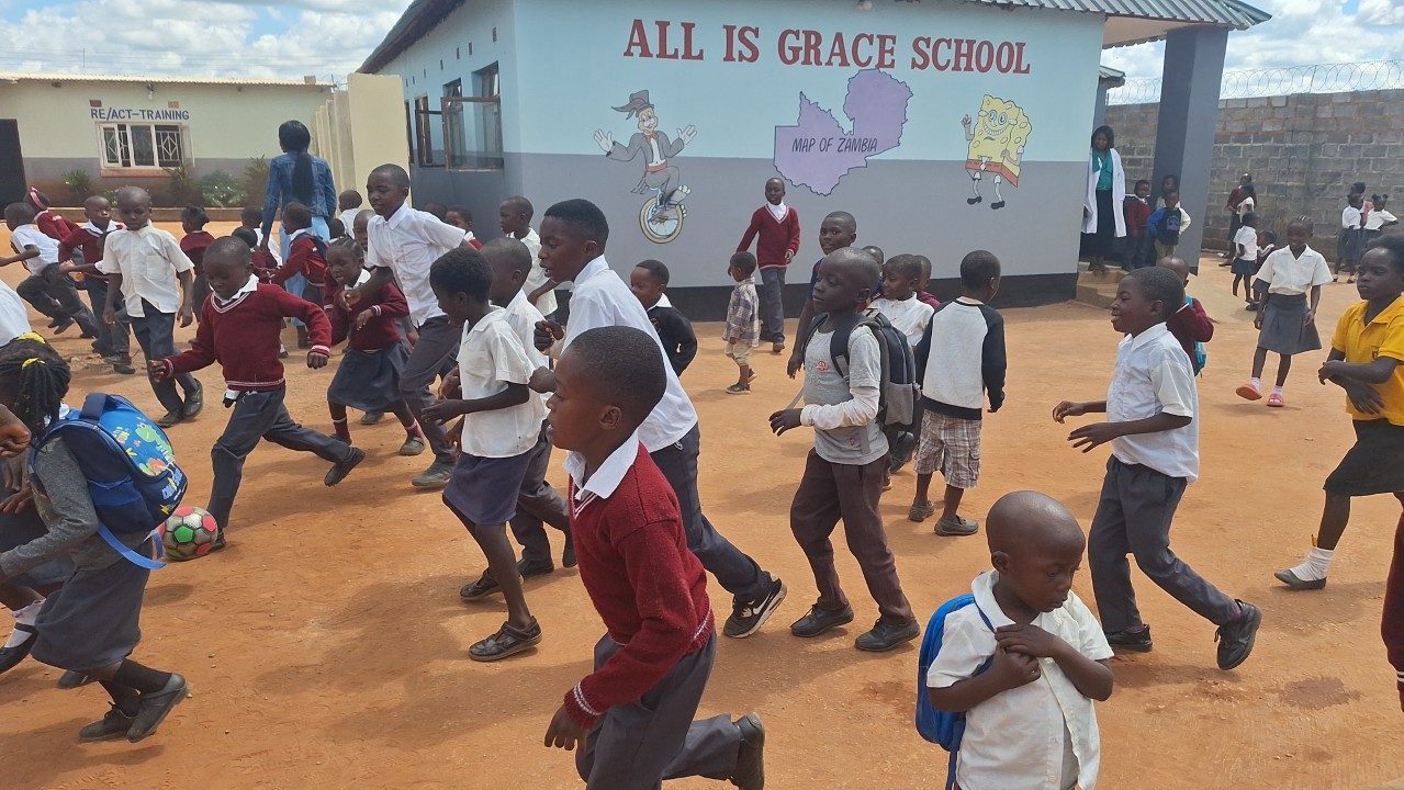 Children playing joyfully outside All Is Grace School, showing the impact of community education