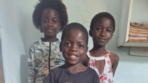 Three children at All Is Grace School wearing donated clothes for school