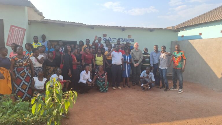 Participants of AGCPI's trauma healing programs pose for a group photo outside the RE/ACT Training center in Zambia.